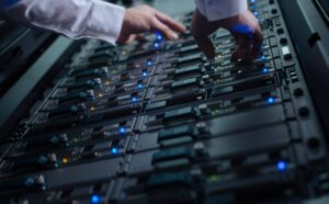 Hände eines Technikers an den Laufwerksschächten eines Server-Racks, Bestandsaufnahme vor der Migration von Windows Server 2016